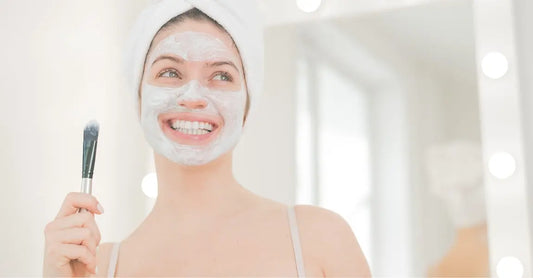 A photo of a young woman smiling with a Simple Body Kaolin Clay Mask on holding a brush.