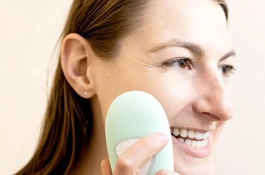 A photo of a Lauren, who is smiling and has beautiful skin, using a Simple Body Facial Cleansing Brush
