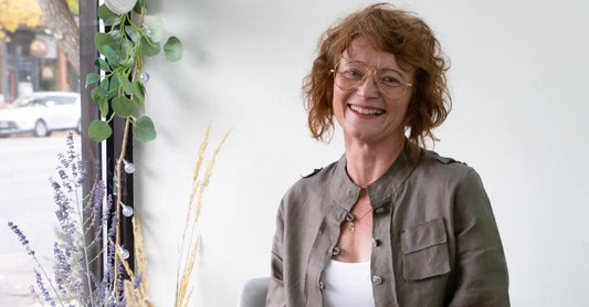 A portrait of Simple Body's Founder, Jewels Burdick wearing a green coat and smiling into the camera.