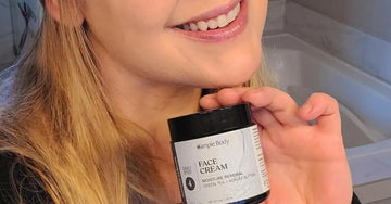 A close-up image of our customer Danica holding a 4oz Simple Body Face Cream and smiling big.