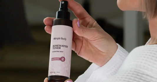 A photo of a woman holding a bottle of Simple Body Rosewater Toner wearing a white waffle robe