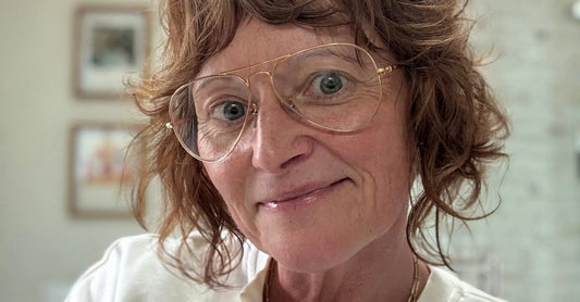 A photo of Simple Body's founder, Jewels Burdick with gold framed glasses smiling. 