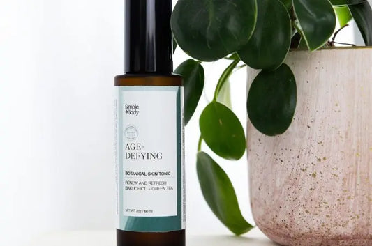 A photo of our Age Defying Botanical Skin Tonic sitting next to a healthy, vibrant plant in a beige ceramic pot.