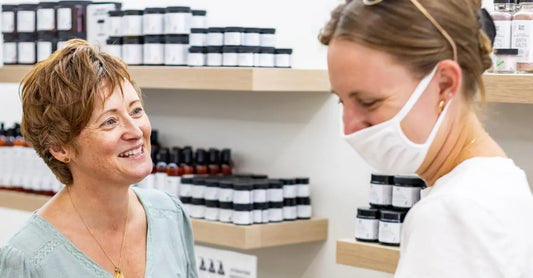 A photo of Jewels, Simple Body Founder, speaking and laughing with one of our customers in front of a shelf full of product.