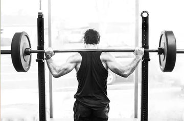 A photo of Morgan, former USOC wrestler, from behind preparing to lift a barbell with two heavy weights.