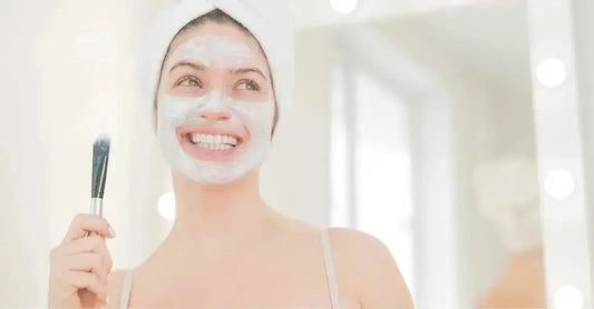 A photo of a young woman smiling with a Simple Body Kaolin Clay Mask on holding a brush.