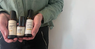 A closeup photo of Jewels Burdick, Founder of Simple Body holding three Simple Body Products including Brighten + Boost Tonic, Barrier Defense Serum and Cleansing Oil