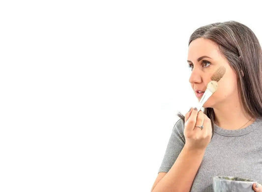 A photo of Kelsey, a former employee of Simple Body looking to the side and applying a Simple Body Clay Mask with a brush.
