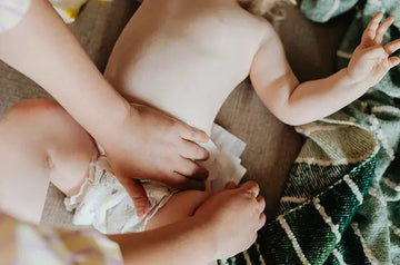 A photo of a mom putting on a new diaper on a young baby with Simple Mama Diaper Balm