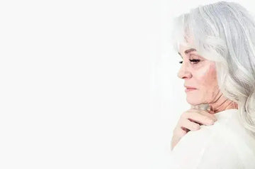 A photo of beautiful Erin Hill looking over her shoulder with silver hair and a hand on her shoulder.