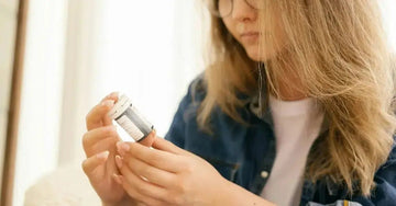 A photo of a young woman trying to read a label of a "natural" skincare product and is confused and our blog title "how to Read Labels and Spot Fake Natural Skincare Products"