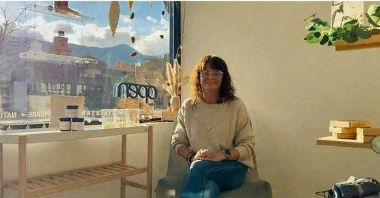 A photo of Jewels Burdick, Founder of Simple Body sitting in a corner of the retail store looking outside to a blue Colorado Sky.