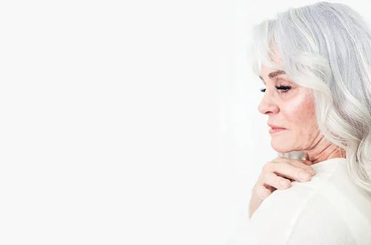 A photo of beautiful Erin Hill looking over her shoulder with silver hair and a hand on her shoulder.