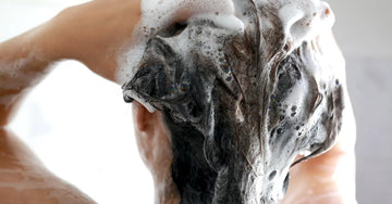 A woman from behind shampooing her hair with lots of bubbles and lather