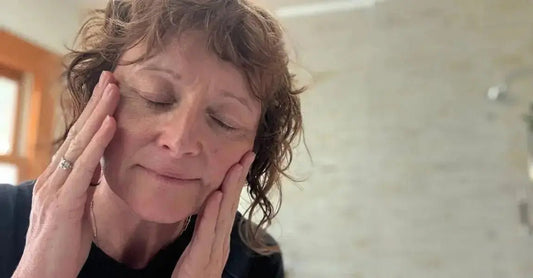 A photo of Jewels, Founder of Simple Body with her eyes closed, massaging her temples as she applies her skincare.