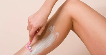 A close up photo of a woman shaving with Simple Body Bamboo Face Polish on her leg.