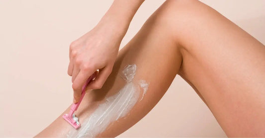 A close up photo of a woman shaving with Simple Body Bamboo Face Polish on her leg.