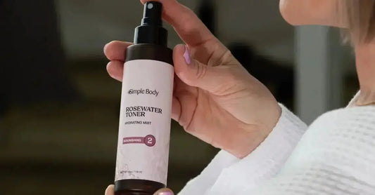 A photo of a woman holding a bottle of Simple Body Rosewater Toner wearing a white waffle robe