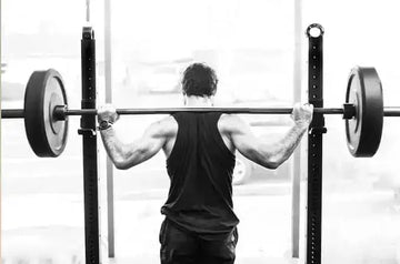 A photo of Morgan, former USOC wrestler, from behind preparing to lift a barbell with two heavy weights.