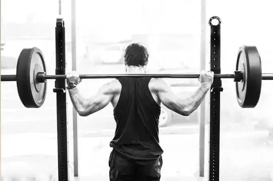A photo of Morgan, former USOC wrestler, from behind preparing to lift a barbell with two heavy weights.