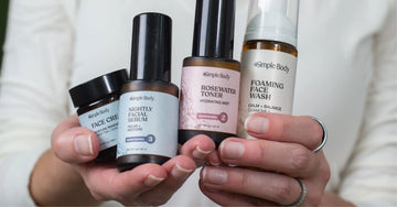 A close up image of hands holding Simple Body Face Cream, Simple Body Nightly Face Serum, Simple Body rosewater Toner and Simple Body Foaming Face Wash in chamomile with a white background.