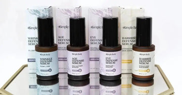 A photo of 4 serum bottles with their boxes including Simple Body Wrinkle Defense Serum, Age Defense Serum, Eye Defense Serum and Barrier Defense Serum sitting on a mirror