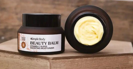A very closeup image of Simple Body Beauty Balm with a full jar on the left and an open jar on the right with the lid off so you can see the creamy yellow texture.
