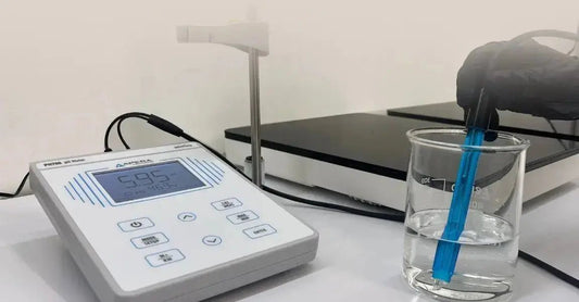 A photo of a ph meter with a Simple Body lab member testing the pH of a liquid in a beaker.