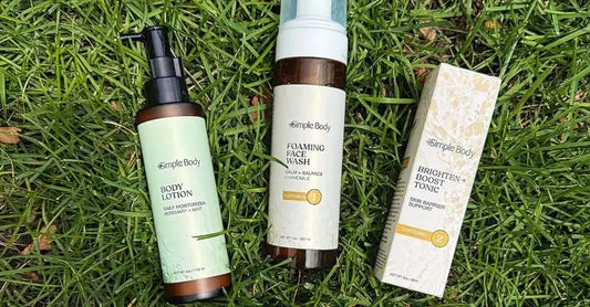 A photo of Simple Body Products laying in the green grass including Rosemary Mint Body Lotion, Chamomile Foaming Face Wash, and Brighten and Boost Skincare Tonic