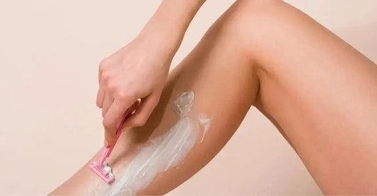 A close up photo of a woman shaving with Simple Body Bamboo Face Polish on her leg.