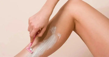 A close up photo of a woman shaving with Simple Body Bamboo Face Polish on her leg.