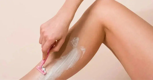 A close up photo of a woman shaving with Simple Body Bamboo Face Polish on her leg.