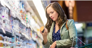 A young woman in a grocery store aisle shops skincare and tries to avoid greenwashing.