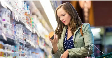 A young woman in a grocery store aisle shops skincare and tries to avoid greenwashing.