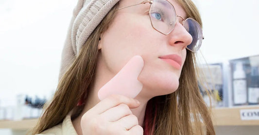A photo of a young woman using a Rose Quartz Gua Sha. 