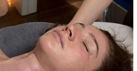 A photo of a woman getting a Simple Body facial lying down with her eyes closed.