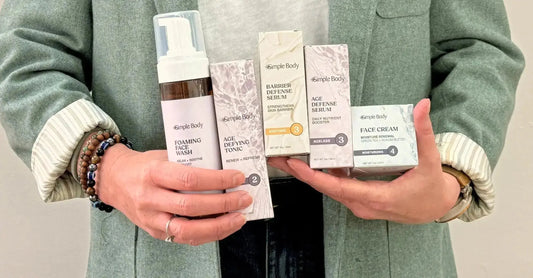 An upclose photo of Simple Body Founder, Jewels Burdick holding a simple skincare routine including Lavender Foaming Face Wash, Age-Defying Tonic, Barrier Defense Seru, Age Defense and Face Cream.