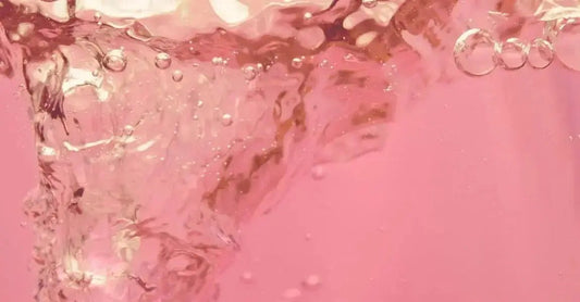 A photo of Simple Body Rosewater Floral toner which is pink and swirling around in a funnel.
