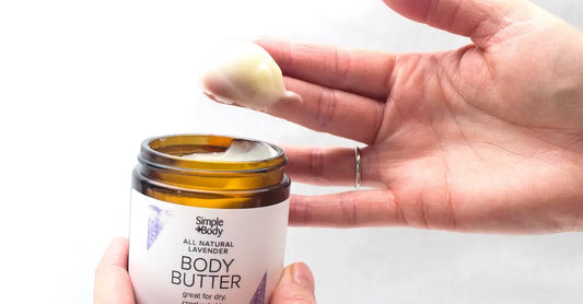 A photo of a woman's hand that has dipped into a jar of Simple Body Lavender Body Butter holding up a big creamy scoop.