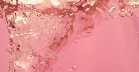 A photo of Simple Body Rosewater Floral toner which is pink and swirling around in a funnel.