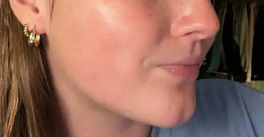 A photo of a beautiful young woman showing how clear, natural skin is beautiful. She'w wearing gold hoops.