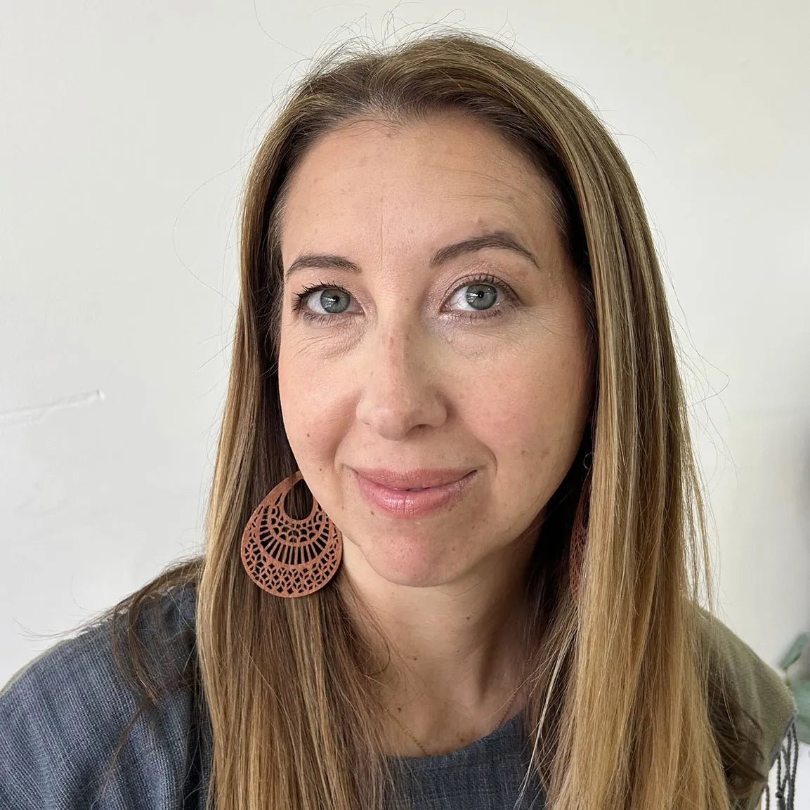 A woman wearing Pure Anada natural makeup with long brown hair on a tan background.