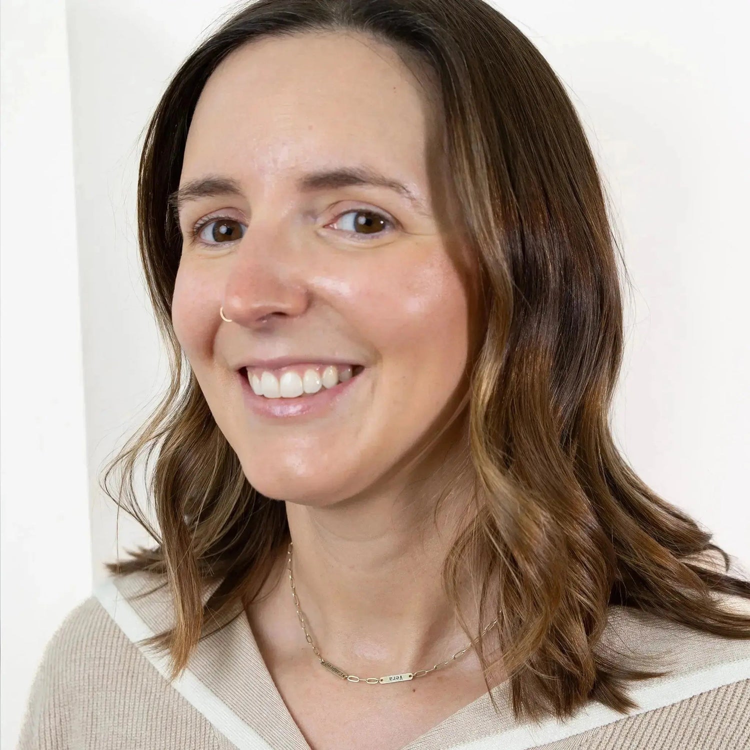 Ashley smiles and shows off her glowing skin after doing her Simple Body skincare routine while staring at you with deep brown eyes.