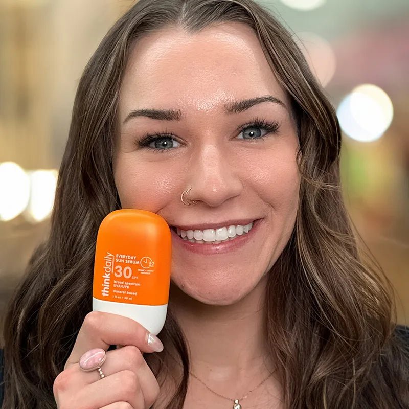 A young woman wi long dark hair holding a Think SPF Sun Serum