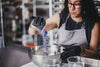 Person in a kitchen pouring purple powder into a bowl