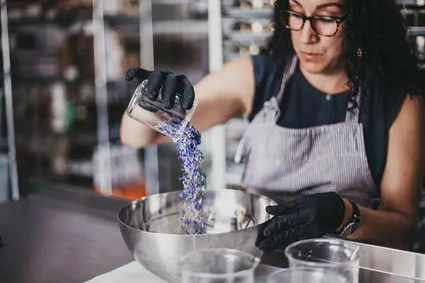 Person in a kitchen pouring purple powder into a bowl