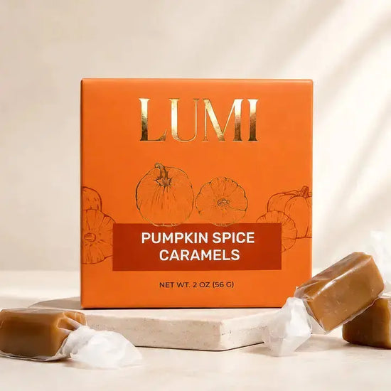 LUMI Pumpkin Spice Caramels in an orange box with gold lettering, styled with unwrapped caramel candies on a light stone surface.