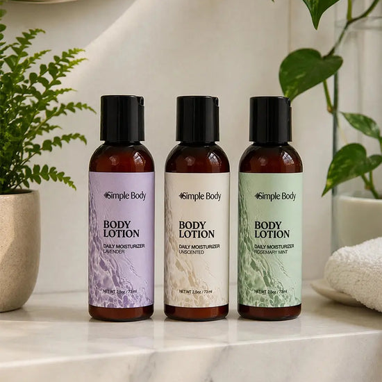Three bottles of Simple Body lotion in a 2.5oz Travel size including Lavender, unscented and Rosemary Mint on a marble surface with plants in the background