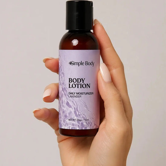 Hand holding a bottle of Simple Body Lavender Travel-Sized Body Lotion against a neutral background