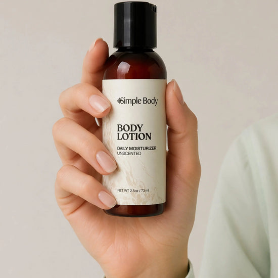 Hand holding a bottle of Simple Body Travel Lotion in Unscented and Fragrance Free against a neutral background. 